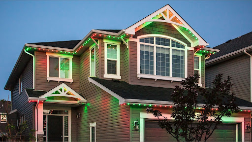 A 2 story house is lit up with alternating red and green permanent LED christmas lights around the roofline on both levels.