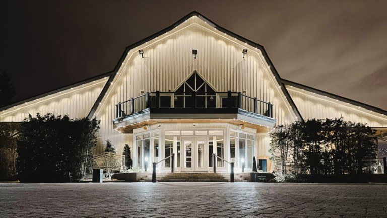 The front entrance of a commercial building lit up with Gemstone Lights in a solid pattern with a warm white colour.