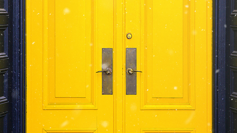 Close up of a brightly painted yellow exterior door.