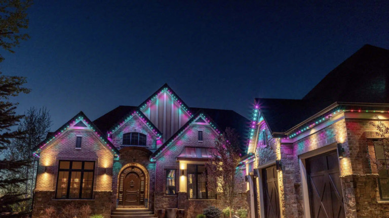 A house with multiple peaks all lit up with pink and blue Gemstone lights for Easter