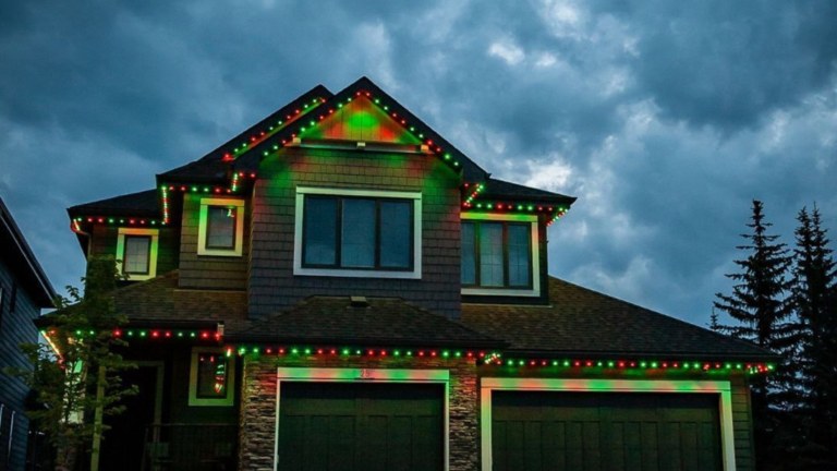 A two story nrick house with red and green gemstone lights on all the roof lines