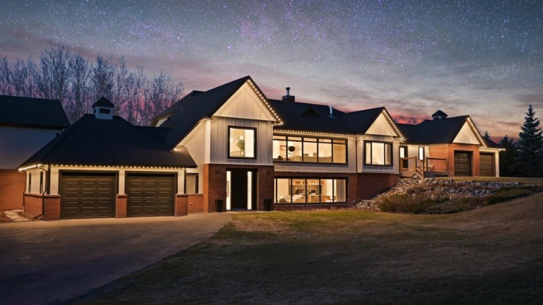 A large 2 storey house is illuminated with Gemstone Lights permanent outdoor LED lights installed by Vibe Illuminations along the front and sides of the house.